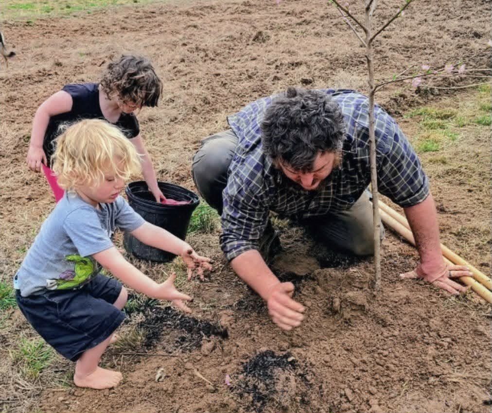 Children planting a tree with an adult